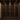 Wine cellar with wooden racks filled with wine bottles against a stone wall.