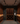 Man in a wine cellar examining bottles with wooden shelves and lighting fixtures.