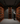 Person in a wine cellar inspecting bottles among wooden shelves.