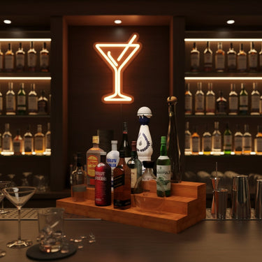 Neon martini glass sign above a bar setup with bottles and glasses.
