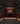 Dark wine cellar with wooden wine racks and bottles.