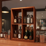 Wooden bar shelf with various bottles of alcohol and glasses on a wooden counter.