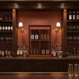 Bar setup with shelves stocked with bottles and glasses, illuminated by wall lights.
