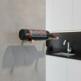 Wine bottle with a label on a wall-mounted holder in a kitchen setting.