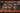 Wooden bar shelf with various bottles of alcohol and glasses on a wooden counter.