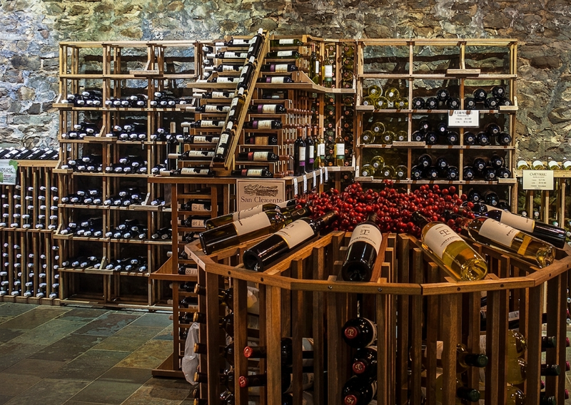 Wine bottles arranged on wooden retail racks in a commercial setting.
