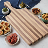 Wooden cutting board with various snacks on a marble surface