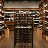 Wine store with wooden shelves and a wine rack displaying various bottles.