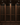 Wine cellar with wooden racks filled with wine bottles against a stone wall.