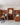 Wine cellar with wooden shelves and a reception desk, featuring people interacting.