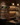 Dark kitchen with wooden walls, hanging bottles, and a bar setup.