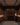 Man in a wine cellar examining bottles with wooden shelves and lighting fixtures.