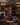 Wine cellar with shelves filled with bottles in a dimly lit room with chandeliers and a fireplace.