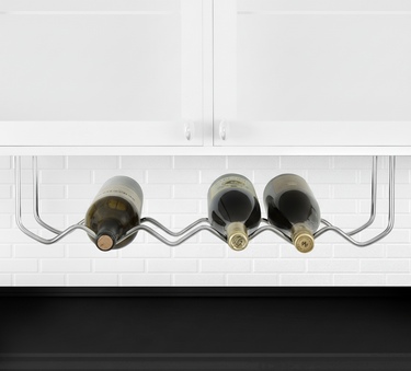 Wine rack holding three bottles of wine under a kitchen cabinet.