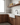 Modern kitchen with wooden cabinets, white countertop, and glass shelves.