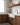 Modern kitchen with wooden cabinets, white countertop, and glass shelves.