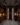Man in a wine cellar with wooden shelves and stone wall.