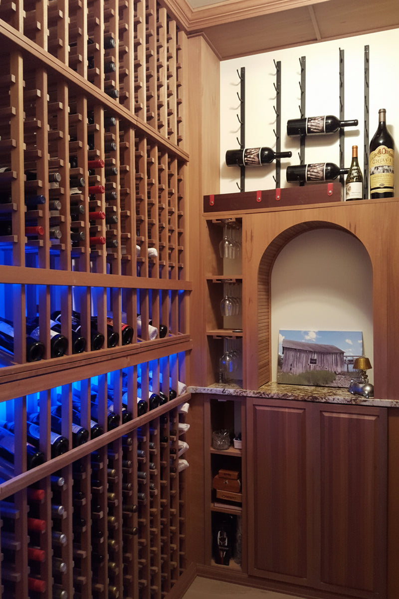 Wooden wine cellar with shelves filled with bottles and a small archway.