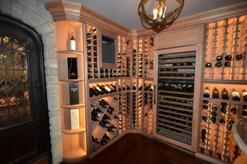 Wine cellar with wooden shelves and glass doors displaying wine bottles.