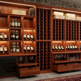 Wooden wine cellar with shelves and bottles against a stone wall.