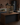 Wooden wine rack on a kitchen island with bottles inside, against a brick wall.