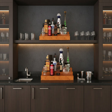 Modern kitchen with dark cabinets, black countertop, and various bottles and glasses.