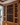 Wooden wine rack with bottles in a room with wooden flooring and a lamp.
